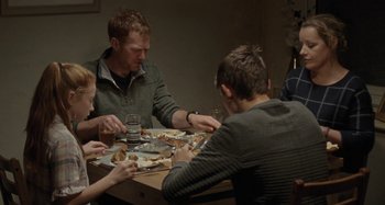 Movie still from “Sorry We Missed You” (2019), directed by Ken Loach – A group of people sitting around a table eating food; Medium shot, Over the shoulder angle