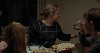 Movie still from “Sorry We Missed You” (2019), directed by Ken Loach – A woman sitting at a table with a plate of food on top of it; Medium shot, Over the shoulder angle