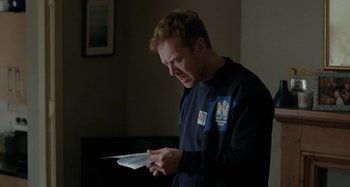 Movie still from “Sorry We Missed You” (2019), directed by Ken Loach – A man holding a piece of paper in his hands; Medium shot, Over the shoulder angle