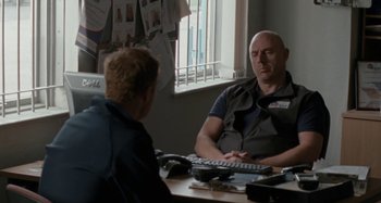 Movie still from “Sorry We Missed You” (2019), directed by Ken Loach – Two men are sitting at a table talking to each other; Medium shot, Over the shoulder angle