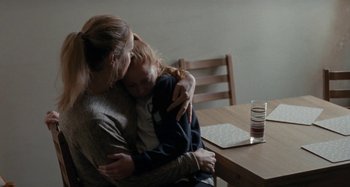 Movie still from “Sorry We Missed You” (2019), directed by Ken Loach – A woman and a child are sitting at a table; Medium shot, Over the shoulder angle