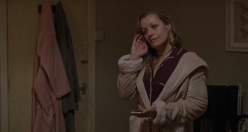 Movie still from “Sorry We Missed You” (2019), directed by Ken Loach – A woman in a robe holding a cell phone in front of a mirror; Medium shot, Over the shoulder angle