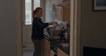 Movie still from “Sorry We Missed You” (2019), directed by Ken Loach – A woman is washing dishes in the kitchen; Medium shot, Low angle