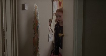 Movie still from “Sorry We Missed You” (2019), directed by Ken Loach – A little girl peeks out from behind a door; Medium shot, Over the shoulder angle