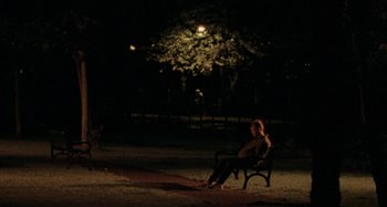 Movie still from “Sorry We Missed You” (2019), directed by Ken Loach – A woman sitting on a park bench at night; Extreme Wide shot, High angle