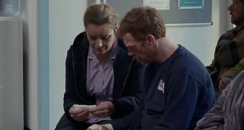 Movie still from “Sorry We Missed You” (2019), directed by Ken Loach – A man and a woman looking at something in a box; Medium shot, Over the shoulder angle