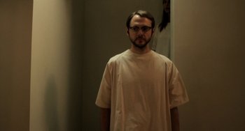 Movie still from “Sound of My Voice” (2011), directed by Zal Batmanglij – A man wearing a white shirt and glasses standing in front of a woman; Medium shot, Low angle