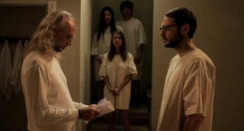 Movie still from “Sound of My Voice” (2011), directed by Zal Batmanglij – A group of people standing in a room; Medium shot, Over the shoulder angle