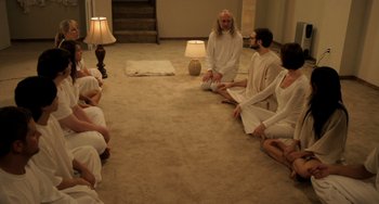 Movie still from “Sound of My Voice” (2011), directed by Zal Batmanglij – A group of people sitting on the floor of a living room; Wide shot, High angle