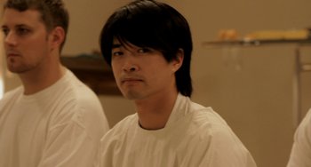 Movie still from “Sound of My Voice” (2011), directed by Zal Batmanglij – A man with long black hair wearing a white shirt; Close Up shot, Low angle