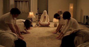 Movie still from “Sound of My Voice” (2011), directed by Zal Batmanglij – A group of people are practicing yoga on the floor; Wide shot, High angle