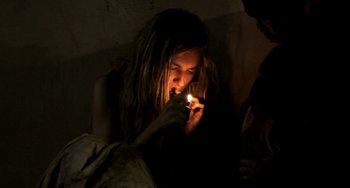 Movie still from “Sound of My Voice” (2011), directed by Zal Batmanglij – A person lighting a candle in a dark room; Close Up shot, High angle