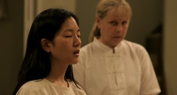 Movie still from “Sound of My Voice” (2011), directed by Zal Batmanglij – Two women in white shirts are meditating in a room; Close Up shot, Over the shoulder angle