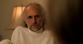 Movie still from “Sound of My Voice” (2011), directed by Zal Batmanglij – An older man with long white hair wearing glasses; Close Up shot, Over the shoulder angle