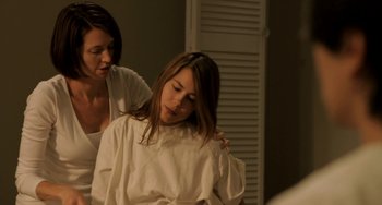 Movie still from “Sound of My Voice” (2011), directed by Zal Batmanglij – A woman in a white shirt is getting her hair combed by another woman; Medium shot, Over the shoulder angle