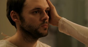 Movie still from “Sound of My Voice” (2011), directed by Zal Batmanglij – A person holding his hand up to his face; Close Up shot, Over the shoulder angle