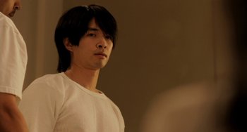 Movie still from “Sound of My Voice” (2011), directed by Zal Batmanglij – A man with long black hair standing in front of a mirror; Close Up shot, Over the shoulder angle