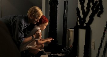 Movie still from “Sound of My Voice” (2011), directed by Zal Batmanglij – A woman and a child playing with a lego set; Medium shot, Over the shoulder angle