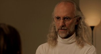 Movie still from “Sound of My Voice” (2011), directed by Zal Batmanglij – An older man with long hair and glasses; Close Up shot, Over the shoulder angle