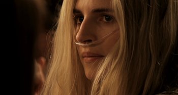 Movie still from “Sound of My Voice” (2011), directed by Zal Batmanglij – A woman with long blonde hair wearing a plastic tube in her mouth; Close Up shot, Over the shoulder angle