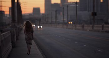 Movie still from “Sound of My Voice” (2011), directed by Zal Batmanglij – A woman walking down the side of the road at dusk; Wide shot, Low angle