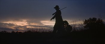 Movie still from “Sounder” (1972), directed by Martin Ritt – A man is walking through a field holding a stick; Wide shot, Low angle