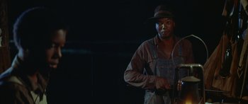 Movie still from “Sounder” (1972), directed by Martin Ritt – A man holding a knife in his hand; Medium shot, Low angle