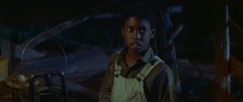 Movie still from “Sounder” (1972), directed by Martin Ritt – A young boy wearing overalls standing in front of a tree; Close Up shot, High angle