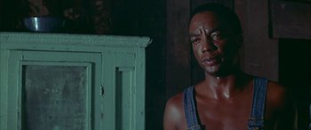 Movie still from “Sounder” (1972), directed by Martin Ritt – A man in a blue shirt is standing in front of a green cabinet; Close Up shot, Low angle