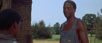 Movie still from “Sounder” (1972), directed by Martin Ritt – A man in overalls standing next to a brick wall; Close Up shot, Over the shoulder angle