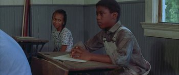 Movie still from “Sounder” (1972), directed by Martin Ritt – A boy and a girl are sitting at a table; Medium shot, Over the shoulder angle