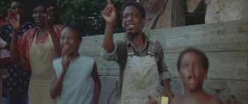 Movie still from “Sounder” (1972), directed by Martin Ritt – A young man holding up his hand while standing in front of a group of people; Medium shot, Low angle