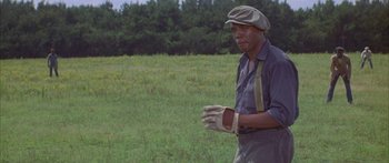 Movie still from “Sounder” (1972), directed by Martin Ritt – A man wearing a hat and gloves standing in a field; Medium shot, Low angle