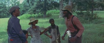Movie still from “Sounder” (1972), directed by Martin Ritt – A group of people standing in the grass; Medium shot, Low angle