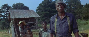 Movie still from “Sounder” (1972), directed by Martin Ritt – A group of people standing next to each other in a field; Medium shot, Low angle