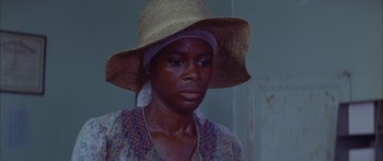 Movie still from “Sounder” (1972), directed by Martin Ritt – A woman wearing a straw hat and a floral dress; Close Up shot, High angle