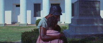 Movie still from “Sounder” (1972), directed by Martin Ritt – A woman and a child are hugging in front of a white building; Medium shot, High angle