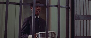 Movie still from “Sounder” (1972), directed by Martin Ritt – A man in a suit and tie holding a metal pan; Medium shot, Low angle