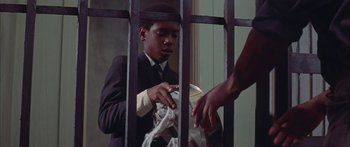 Movie still from “Sounder” (1972), directed by Martin Ritt – A man in a suit and tie holding onto a rope in a jail cell; Medium shot, Low angle
