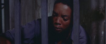 Movie still from “Sounder” (1972), directed by Martin Ritt – A man is looking through a metal fence; Close Up shot, High angle