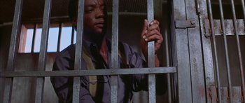 Movie still from “Sounder” (1972), directed by Martin Ritt – A man in a jail cell with his hands on the bars; Medium shot, Low angle