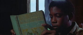 Movie still from “Sounder” (1972), directed by Martin Ritt – A young boy holding a book in his hands; Close Up shot, Low angle