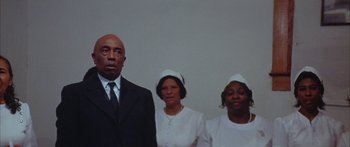 Movie still from “Sounder” (1972), directed by Martin Ritt – A man and two women standing in front of a white wall; Medium shot, Low angle