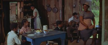 Movie still from “Sounder” (1972), directed by Martin Ritt – A family sitting at a table in a room; Wide shot, Over the shoulder angle
