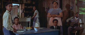 Movie still from “Sounder” (1972), directed by Martin Ritt – A group of people standing around a table; Medium shot, Low angle