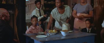 Movie still from “Sounder” (1972), directed by Martin Ritt – A group of people sitting at a table with food on top of it; Medium shot, Over the shoulder angle