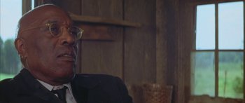 Movie still from “Sounder” (1972), directed by Martin Ritt – An older man sitting in front of a wooden wall; Close Up shot, Low angle