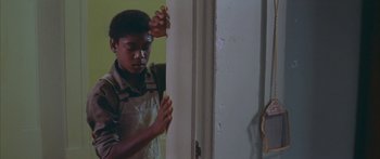 Movie still from “Sounder” (1972), directed by Martin Ritt – A young boy standing in front of an open door; Medium shot, High angle