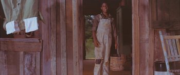 Movie still from “Sounder” (1972), directed by Martin Ritt – A man in overalls standing next to a barrel; Medium shot, Low angle