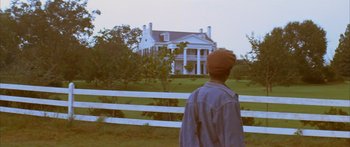 Movie still from “Sounder” (1972), directed by Martin Ritt – A person standing in front of a white house; Wide shot, Low angle